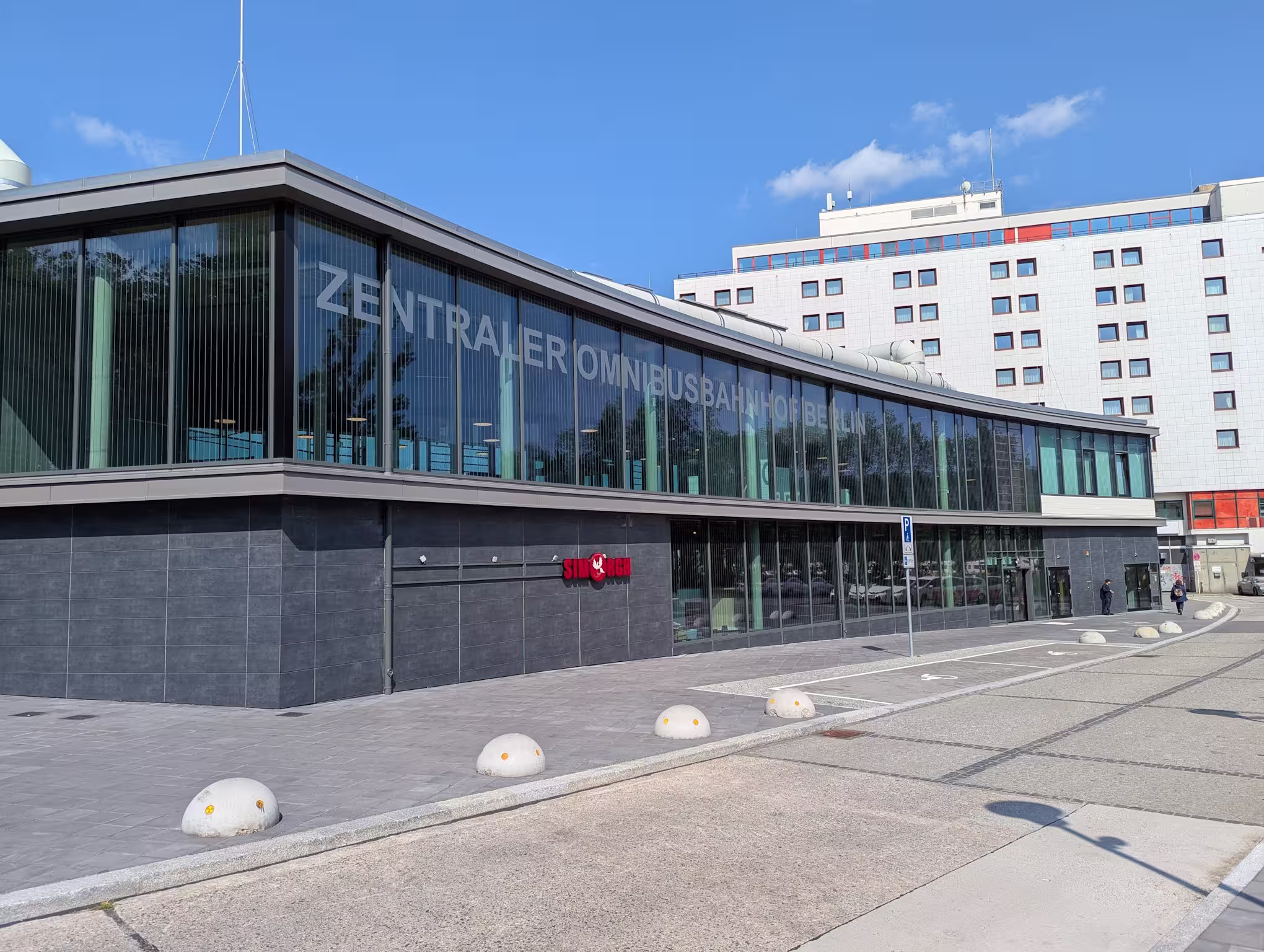 The ZOB waiting hall from the outside with two disabled parking spaces in front and the ibis hotel in the background